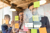 Drie mensen achter glas met post-its en aantekeningen